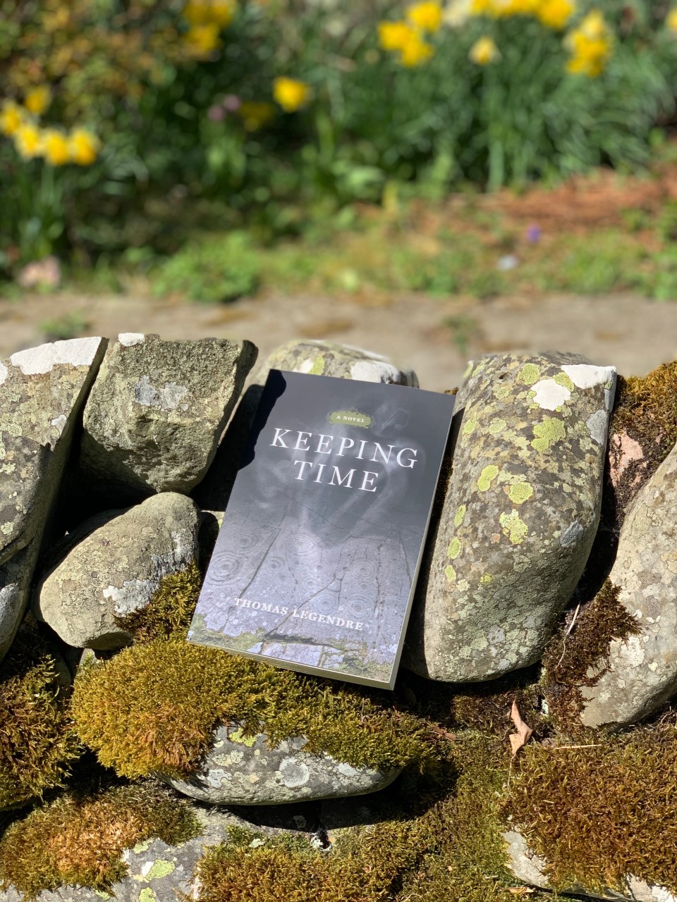 A copy of Keeping Time resting on a stone wall.