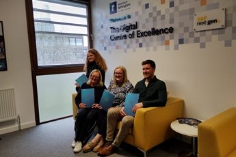 Programme participants from Midlands Engine sit together on a yellow sofa in the Digital Centre of Excellence holding their certificates of attendance.
