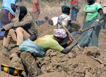 An african woman with baby on back mining