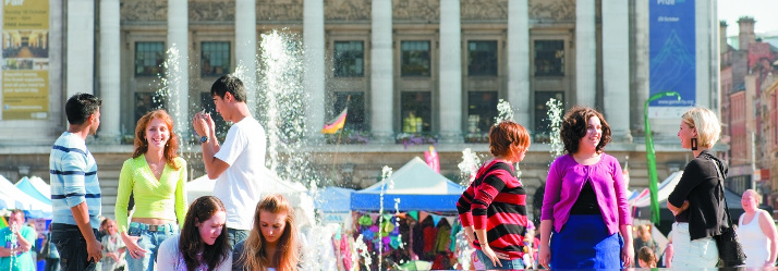 Undergraduate students by fountains on Market Square with Nottingham Council House in the background, Nottingham 714x249