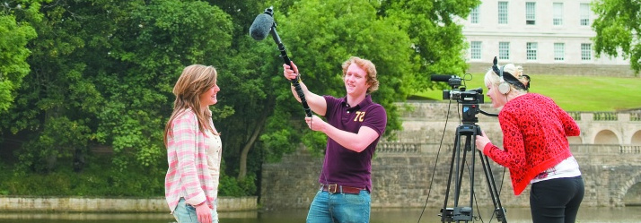 Undergraduate students filming by Highfields lake in front of Trent Building 714x249