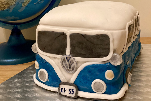 A photo of a home made blue and white camper van birthday cake baked to brighten and celebrate a lockdown birthday.