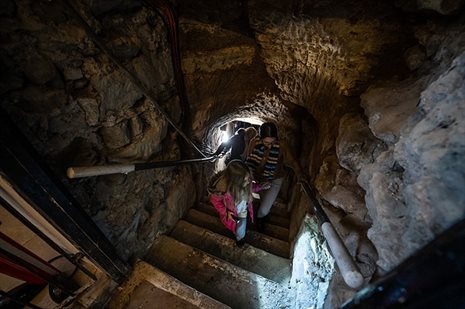 An adult and child ascending steps through a cave system.