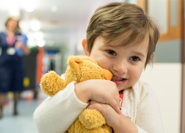 Young CBTRC patient Olivia clutching her teddy bear
