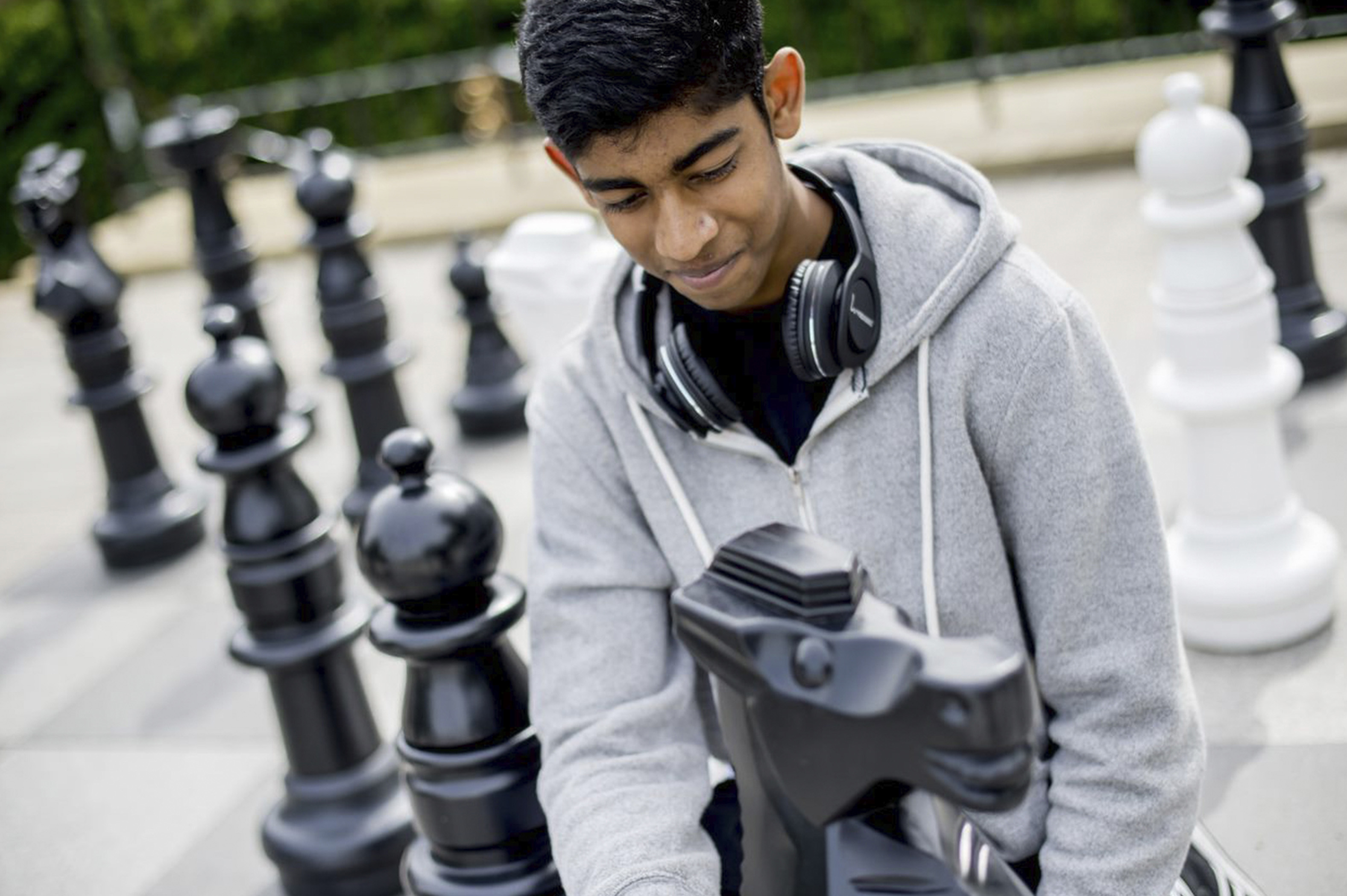 An undergraduate student playing giant chess outdoors on campus