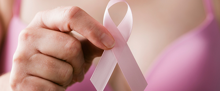 A person in a pink bra holding a pink awareness ribbon