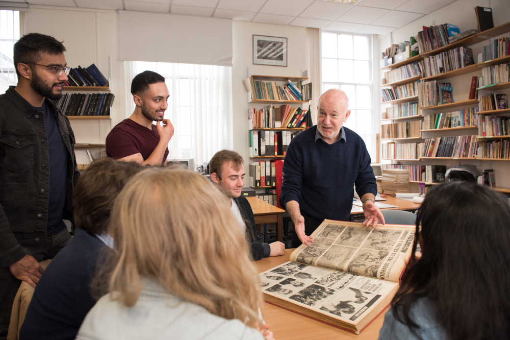 Mixed academic group looking at archive of newspapers