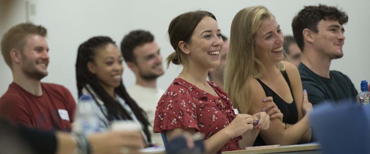 Mature undergraduate students smiling, sat at a desk