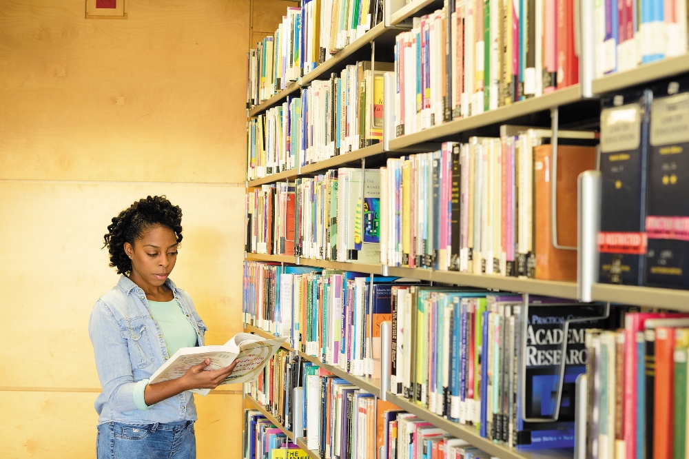 A female student reading a book in a library