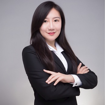 Photo of Junyi Xiao, International Business Alumni (2017), wearing a black suit and white shirt, standing with her arms crossed.