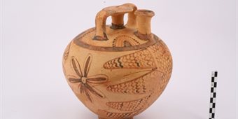 Stirrup jar from the Mycenean tomb chamber at Epidaros - a pale round terracotta jog with darker floral carvings/decorations