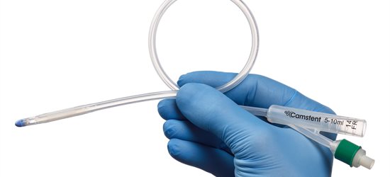 A hand holding a urinary catheter