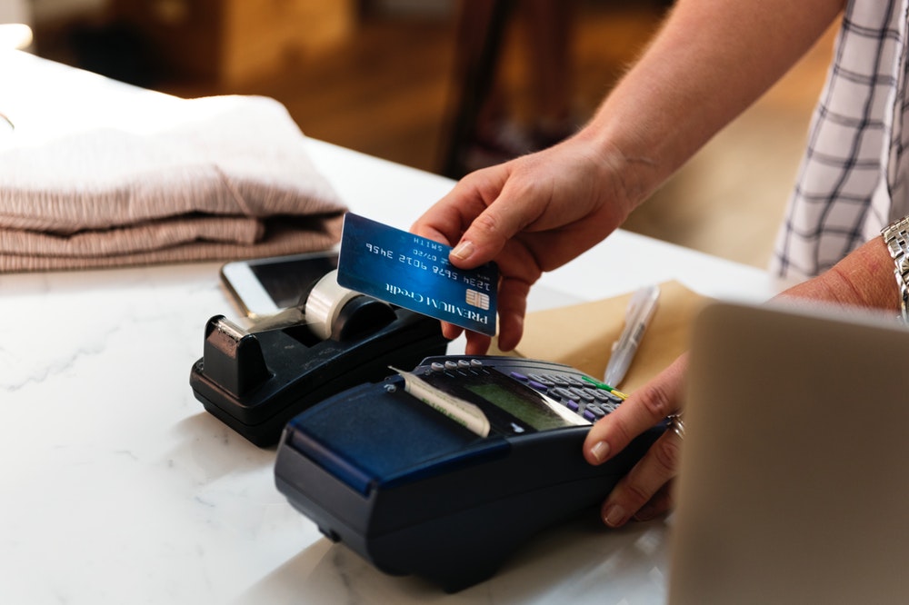Person holding a credit card and a payment device