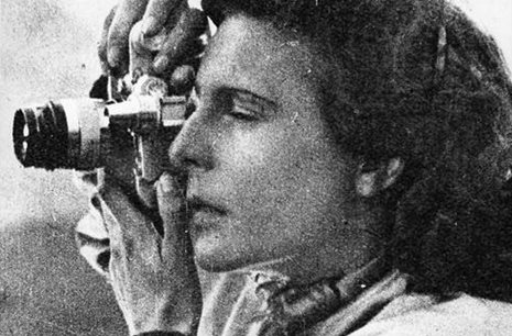 Black and white image of a woman taking a photograph