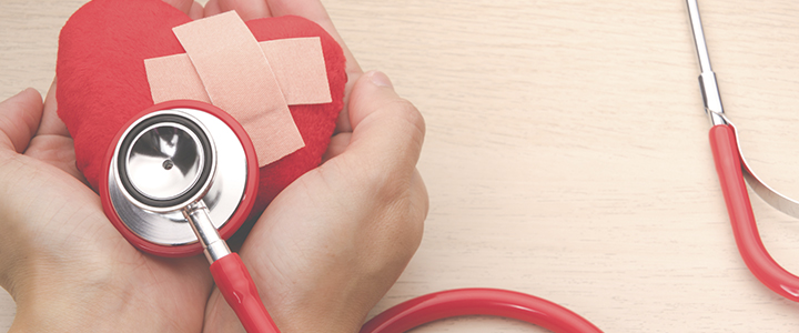 Red stethoscope on a felt heart with plasters on it being held in someone's hands