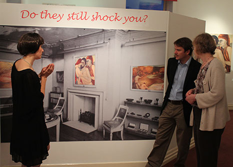 Group of people looking at a large image of a room with a banner above that reads "Do they still shock you?"