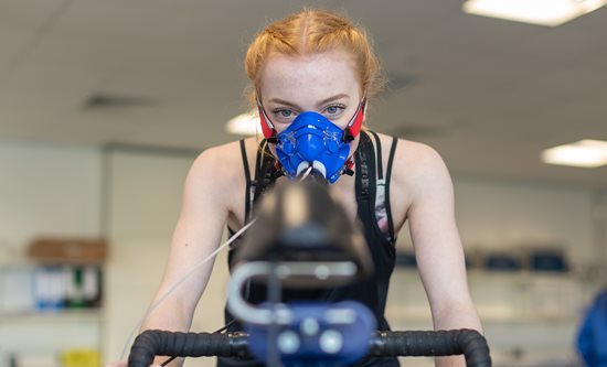 Research volunteer wearing oxygen mask and performing exercise test on cycle ergometer