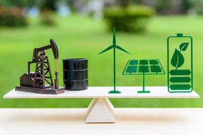 Close-up photograph of a set of small wind turbine, solar panel etc. figurines atop a set of balanced scales