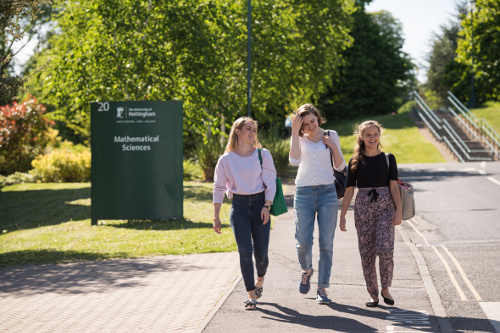 Three students walking past Mathematical Sciences sign