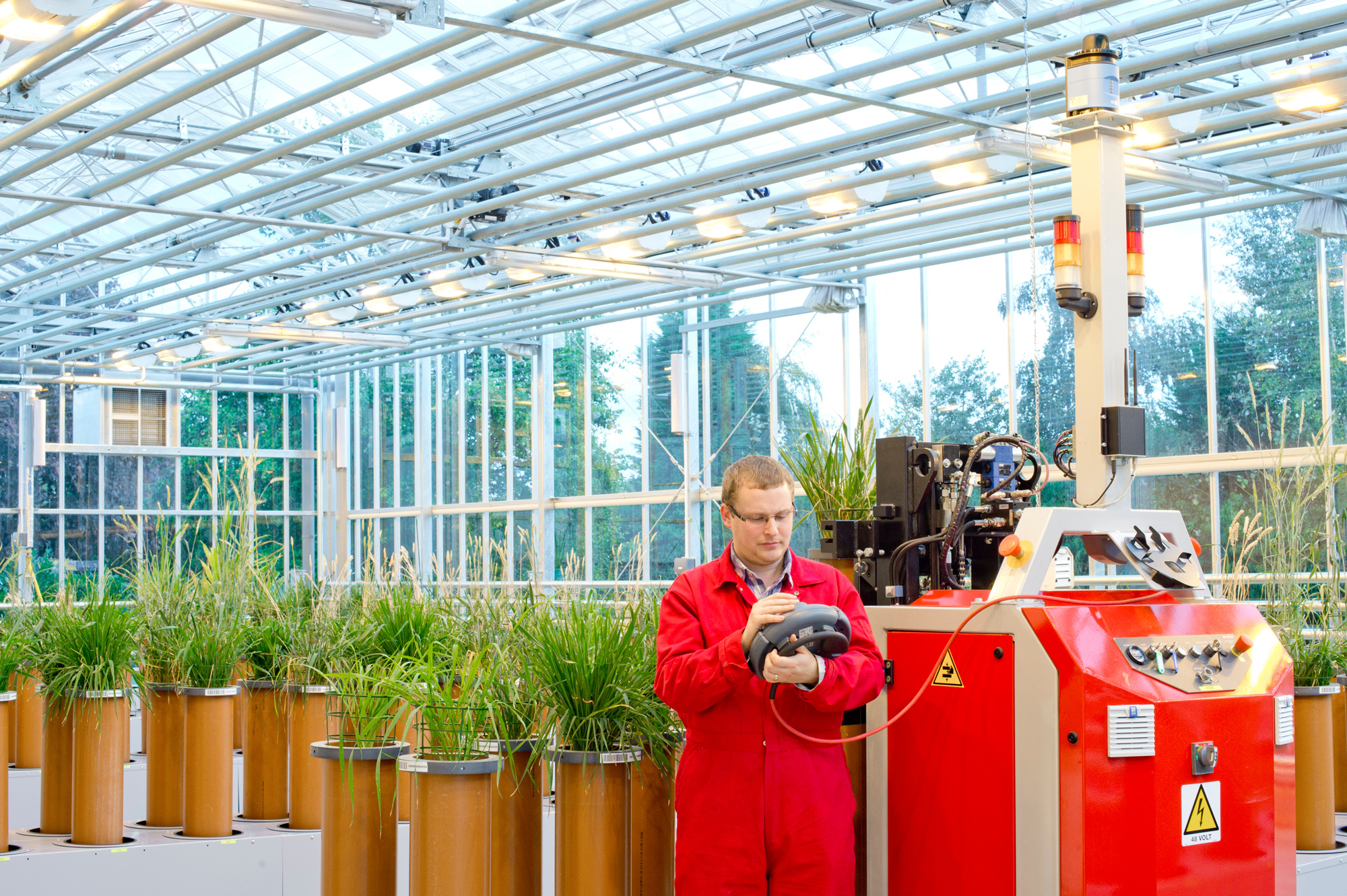 A student working on machinery in a greenhouse 