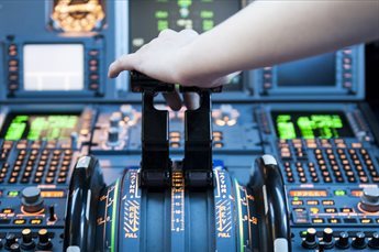 A close-up of an aeroplane cockpit, with the pilot having their hand on one of the controls.