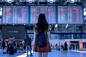 A woman looking at a departures and arrivals board at an airport