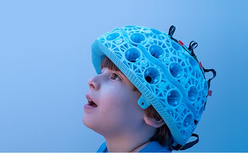 Child in awe wearing brain scanner.