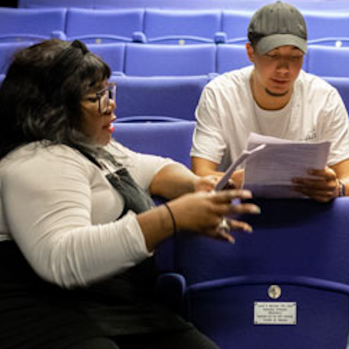Two students reading a script sitting in theatre