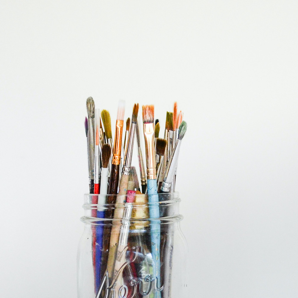 Collection of paintbrushes in a jar standing brushes up