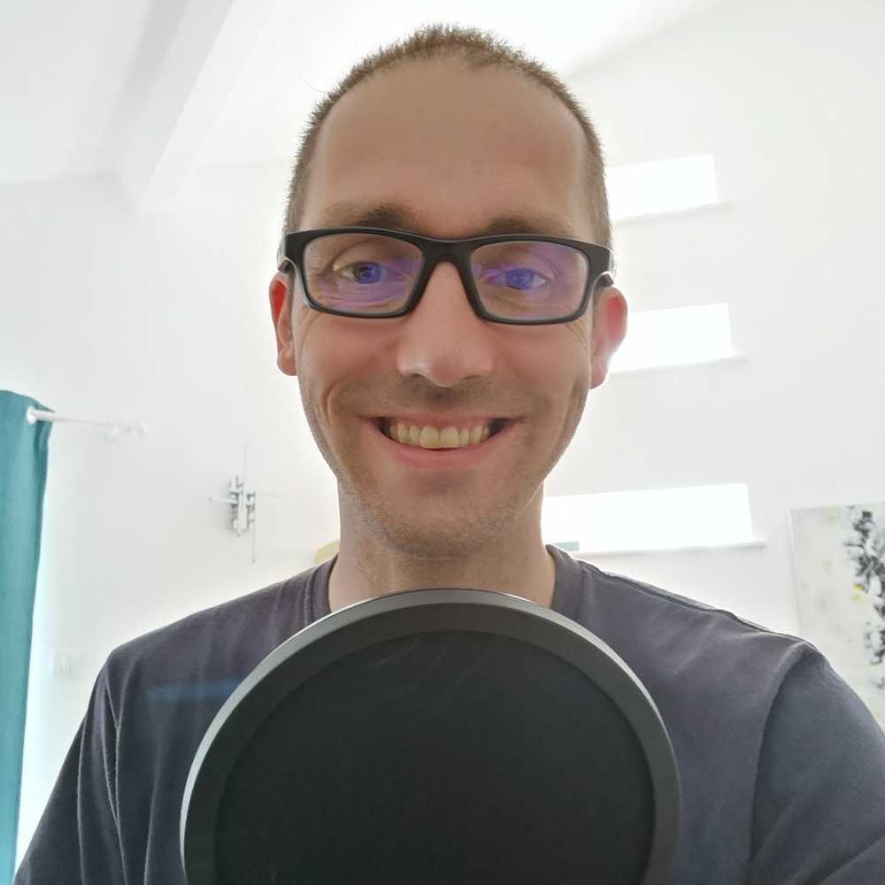 A photo of Pierre-Alexis Mével sitting behind a round microphone.