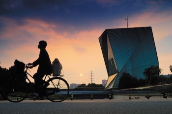 Silhouette of a person on a bicycle at sunset with the Centre for Sustainable Energy Technology (CSET) in Ningbo, China in the background