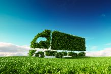 Eco friendly transportation concept green truck icon on fresh spring meadow with blue sky in background.