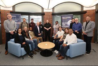 A group photo of cohort 16 of the Help to Grow: Management course. The participants stand and sit together with members of the course delivery team in a brightly lit seating area.