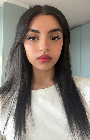 Head and shoulders photo of Zaynab Janmohamed. Zaynab is wearing a white top and has long dark hair.