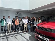Photo of the participants of the MSc Consultancy Competition - 2025, visiting Jaguar Land Rover. There is the bonnet of a red Range Rover in the foreground of the photo to the right, with the participants stood in the background.