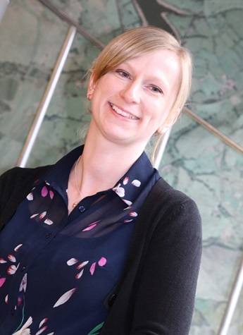A profile photo of Gemma Black. She has blonde hair and wears a floral shirt with a cardigan, and she is looking off to one side and smiling.