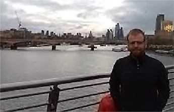 Photo of Dr James Crick. James is stood on a bridge with a river in the background.