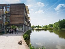 Photo of Jubilee Campus. Buildings are on the left of the image with the campus walkway visible and the lake and trees are to the right..