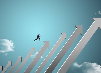 A businessman jumping on growing chart with sky background