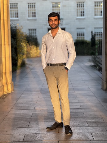 Anudeep Sridhar standing with his hands in cream trouser pockets, white shirt