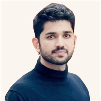 Harsh Janakkumar Shah with short dark hair and beard wearing a dark blue polo neck jumper