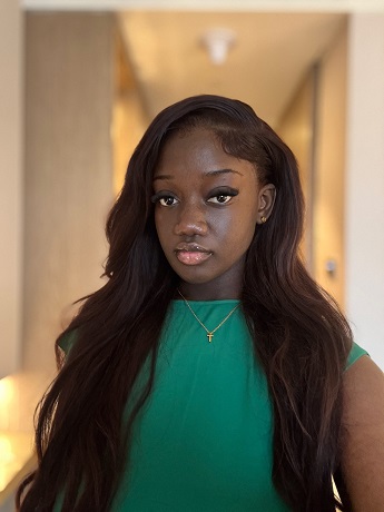 Kirsten Lartey with long dark brown hair and wearing a bright green top and necklace