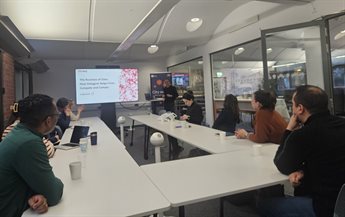 Participants from Pecege sit at desks as they listen to a member of Datagum present. The desks are arranged in a horse shoe layout and a presentation screen at the front of the room features the title 'The business of data: How datagum helps firms compete