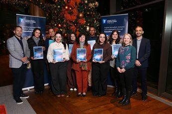 Participants from Pecege stand together in a group with members of the Executive Education team, holding their participation certificates.In the background, a large Christmas tree and two Executive Education banners are visible.