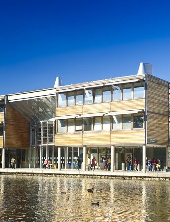 Wooden and glass buildings on Jubilee Campus behind the lake, blue skies