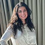 Head and shoulders photo of Dayana El Nsouli. Dayana has long dark hair, is wearing a cream coloured blouse and is smiling.