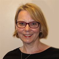 Head and shoulders photo of Mihaela Keleman. Mihaela has blond hair, she is smiling and she is wearing a black top and glasses.