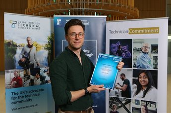 Ben Gridley holding his end-of-programme completion certificate in front of Nottingham University Business School, ITSS and Technician Commitment branded banners