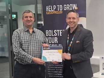 Help to Grow: Management course participant Richard Major receives his completion certificate from Nick Proverbs, Executive Education. They hold the certificate between them and both smile at the camera.