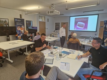 Participants from the third Ultimate Scale Up cohort sit around tables discussing ideas during a workshop.